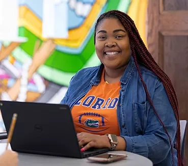 Student smiling while typing on laptop